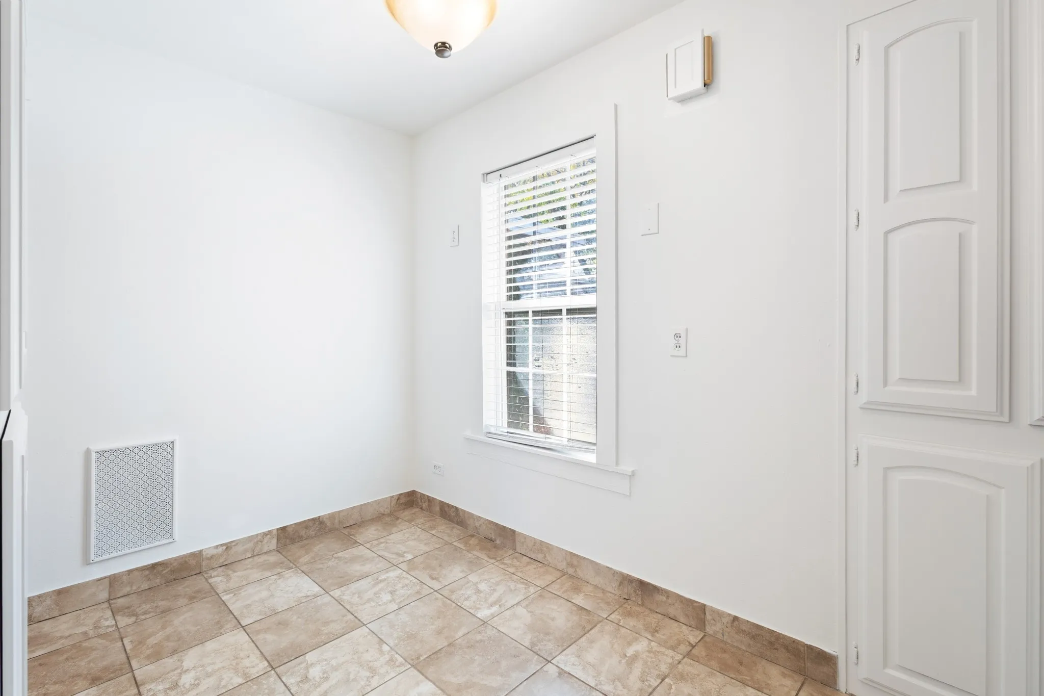 Neutral-toned tile flooring, integrated storage cabinetry, and a window with blinds