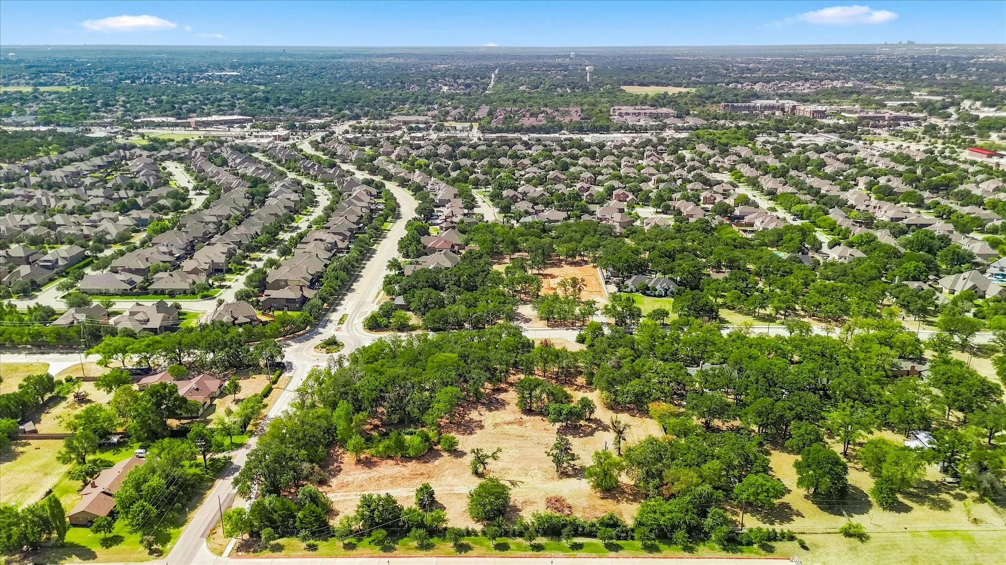 Expansive land parcel with abundant mature trees and undeveloped terrain, surrounded by established residential areas and roadways