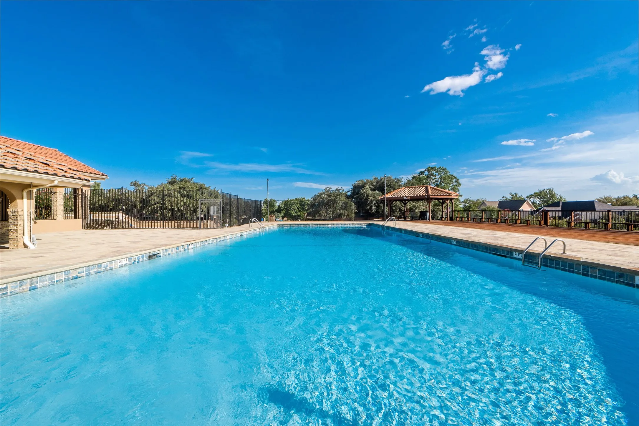Expansive outdoor swimming pool with integrated entry steps and a surrounding paved deck