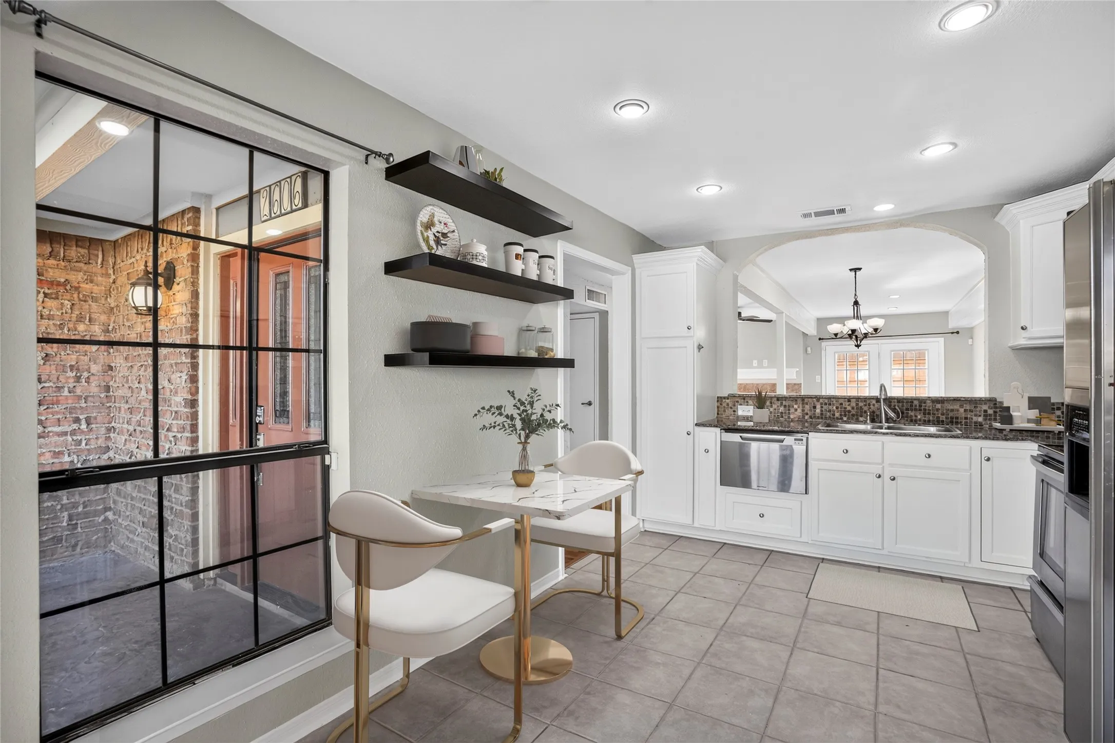 White cabinetry with a tile backsplash and dark countertops