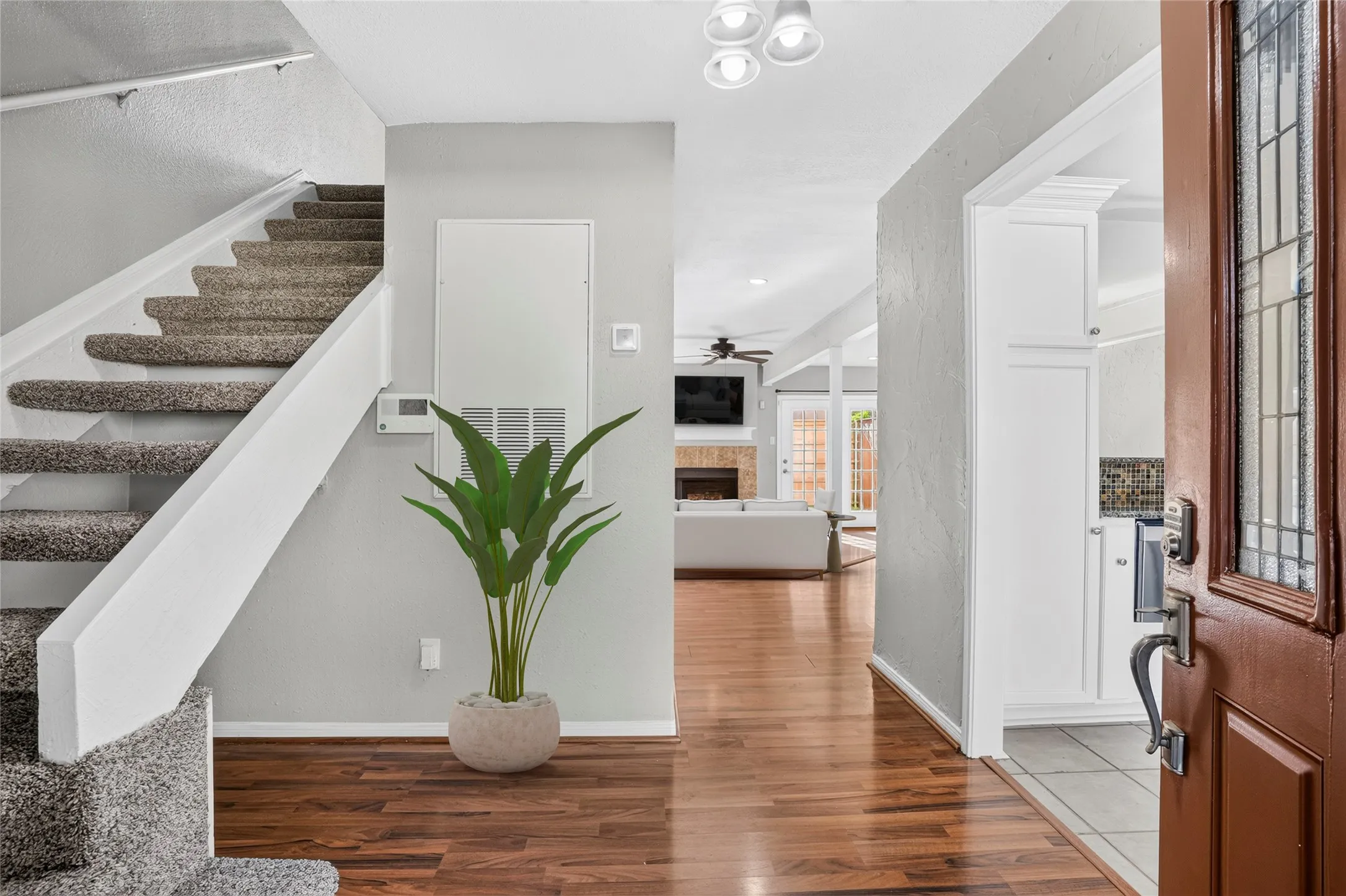 Hardwood-finish flooring, carpeted staircase, recessed lighting, white cabinetry, and stained glass door panel