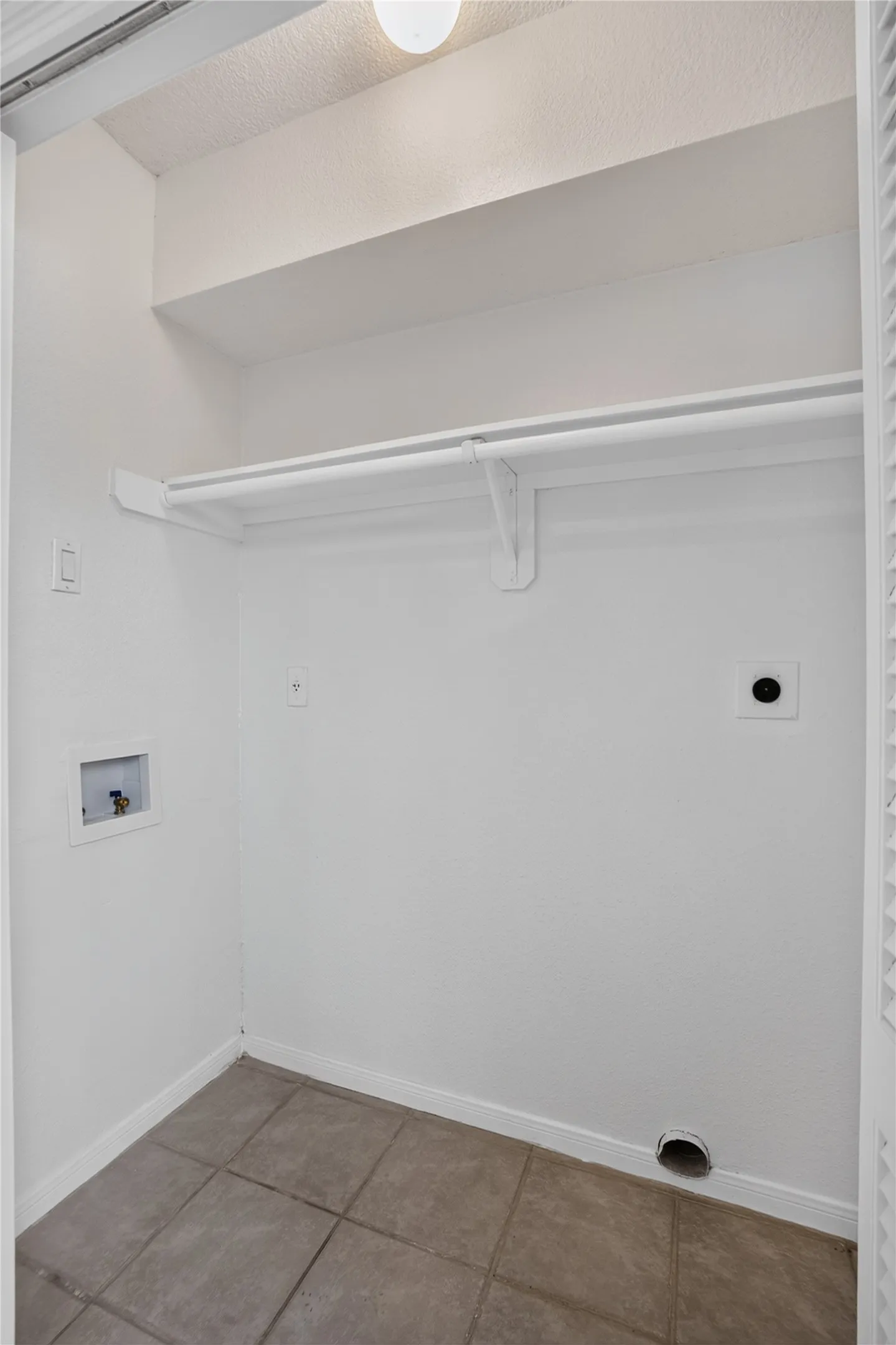 Utility closet featuring a clothing rod, recessed ceiling light, and tile flooring