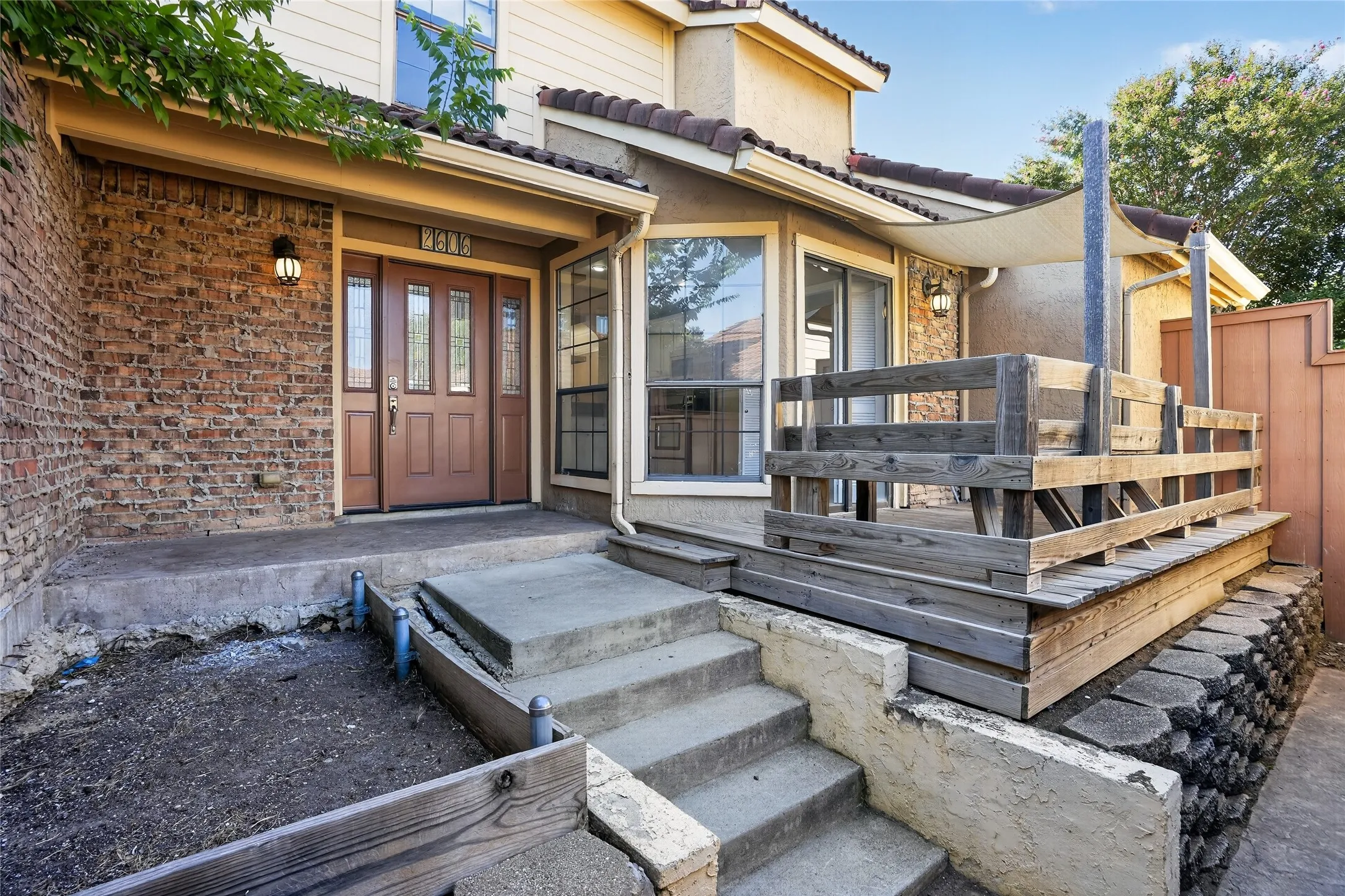 Brick facade with a covered entry, wood-paneled front door with sidelights, and a multi-level concrete staircase