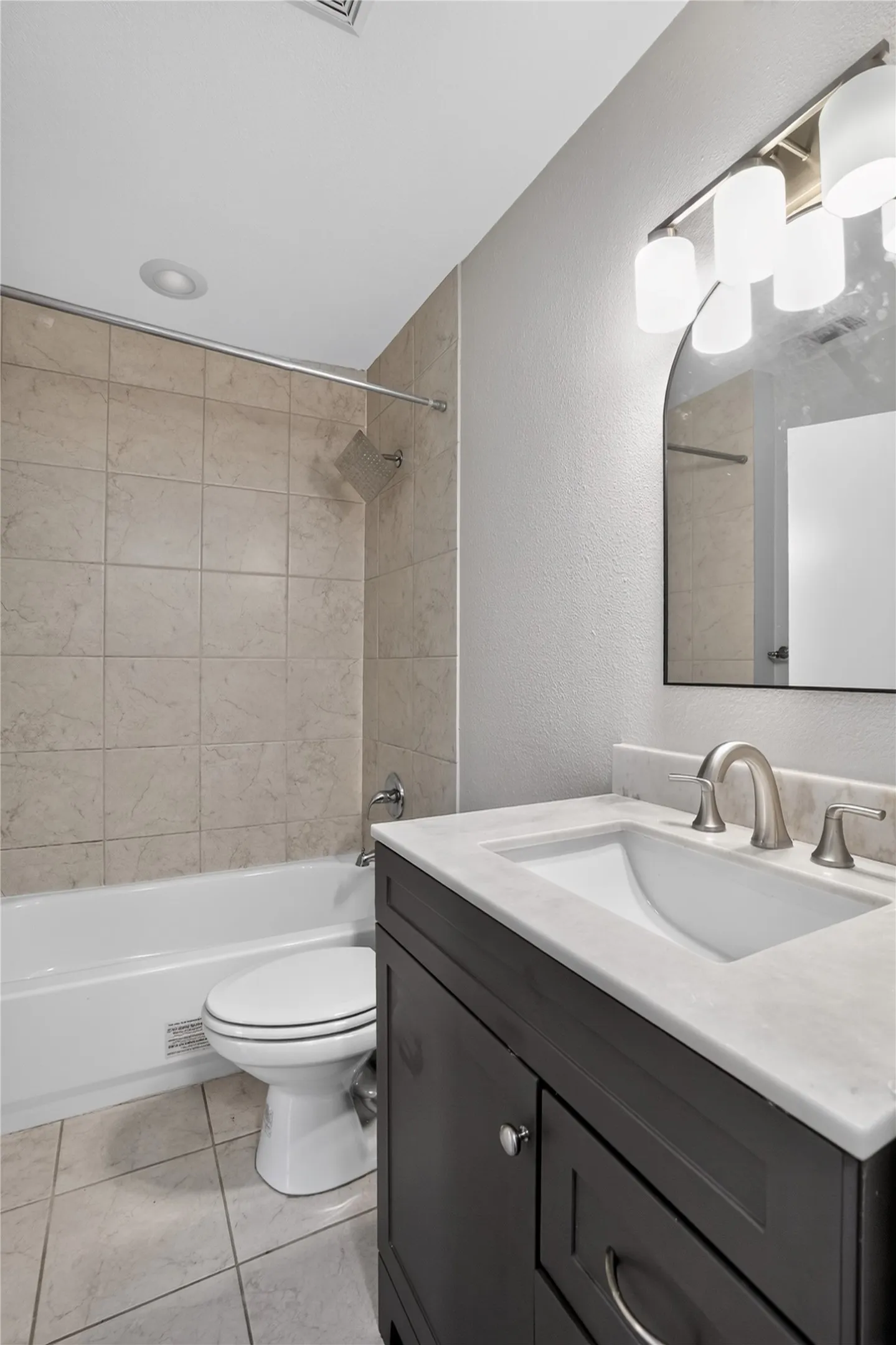 Vanity with a white countertop and integrated sink, brushed nickel faucet, and a wall-mounted arched mirror