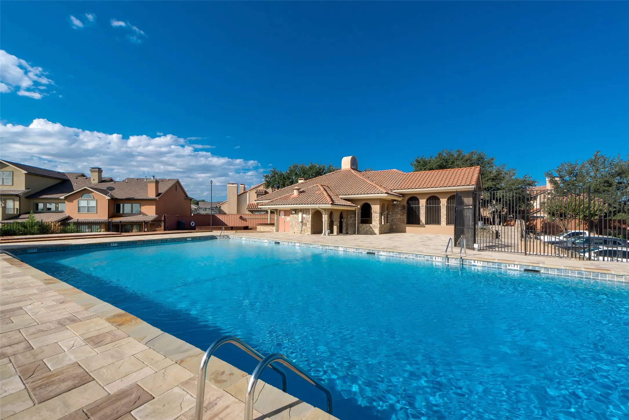 Outdoor swimming pool with integrated steps, tile coping, and surrounding paver decking
