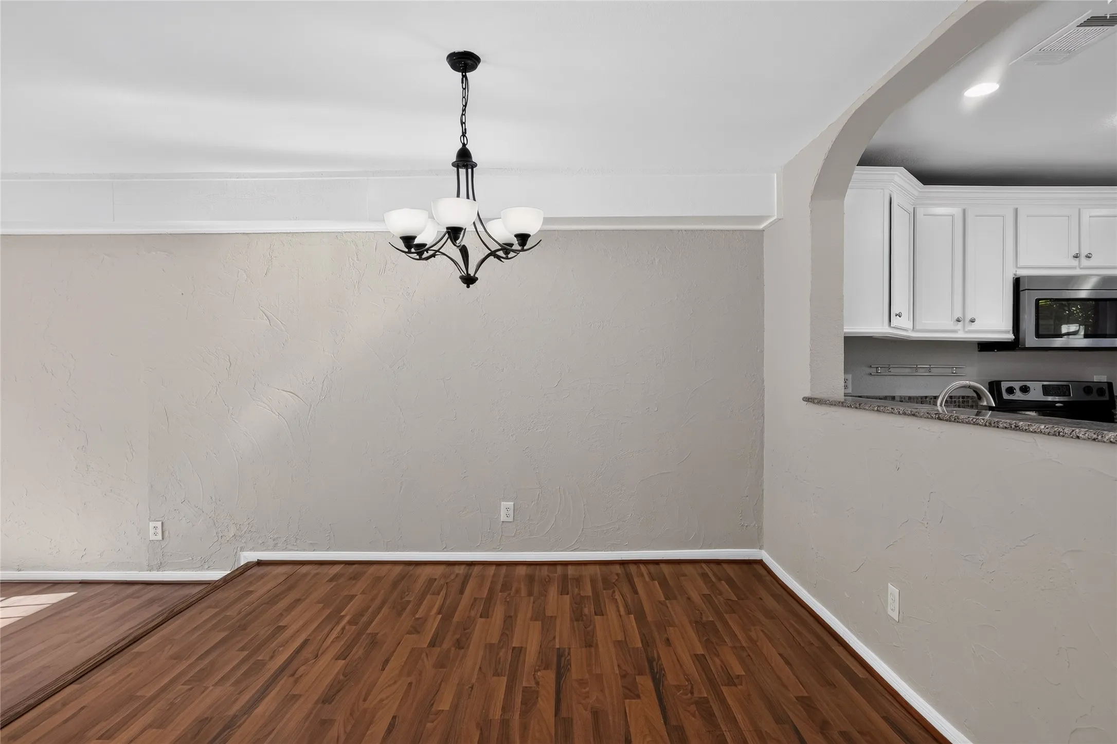 Hardwood-style flooring throughout, coved ceiling molding, and a five-light chandelier
