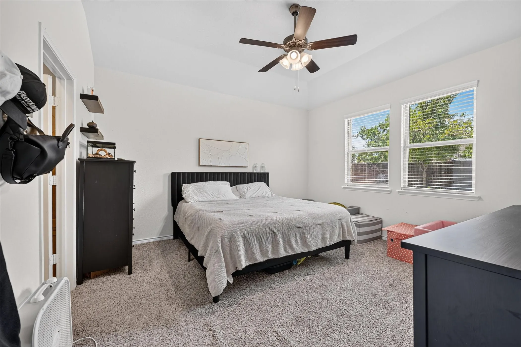 Vaulted ceiling with a ceiling fan, two windows, wall-to-wall carpeting, and white walls
