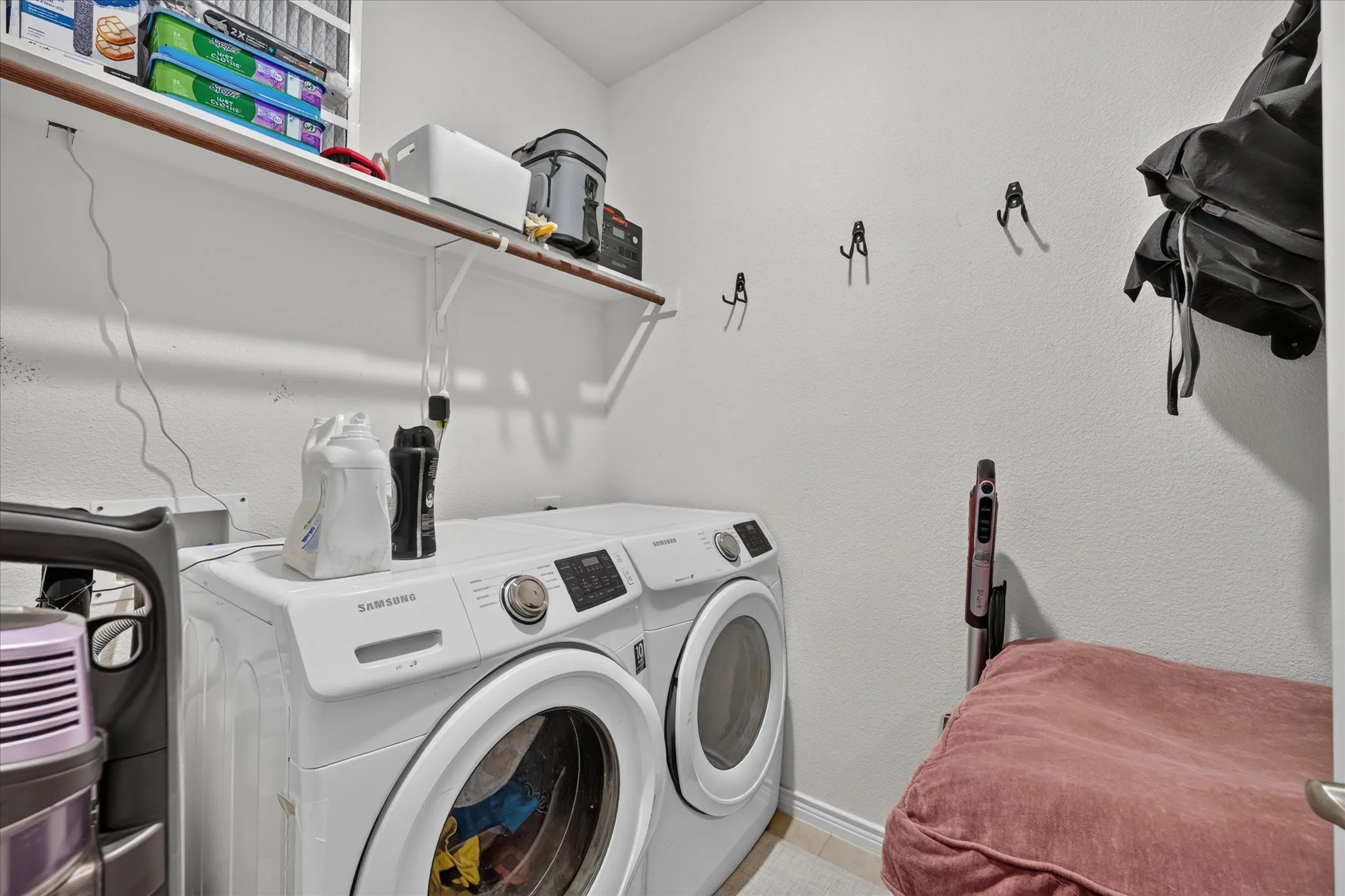 Dedicated utility area with wood-finish flooring, featuring a built-in shelf for storage and multiple wall-mounted hooks
