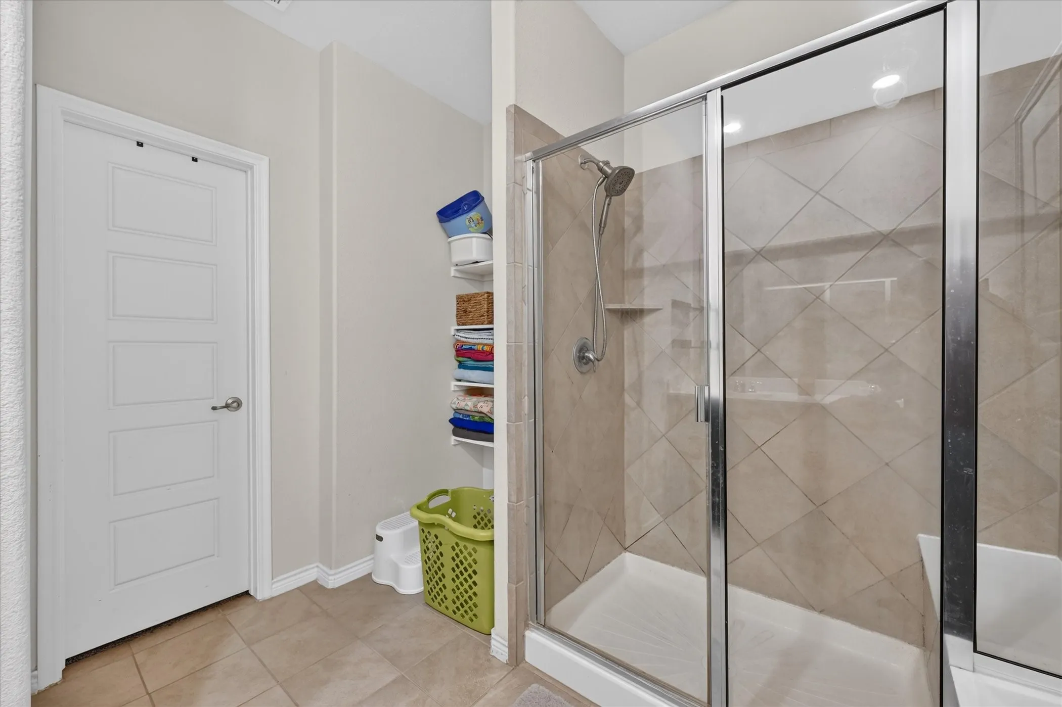 Walk-in shower with glass enclosure, tiled walls, and built-in shelving