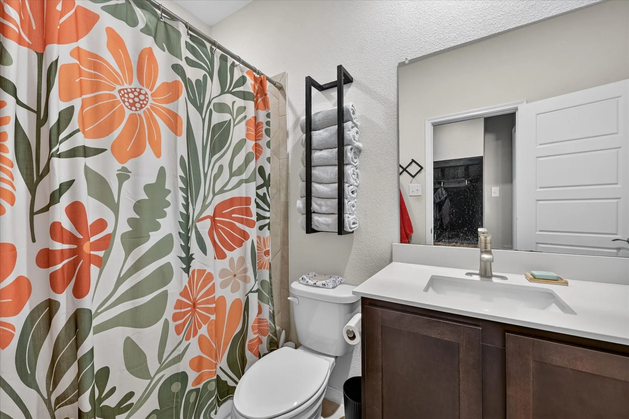 Dark wood-finish vanity with a single basin sink, brushed nickel faucet, and a wall-mounted rectangular mirror