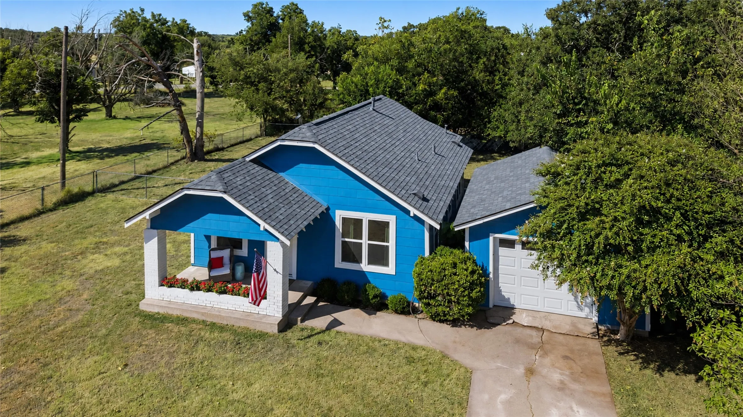 Blue siding exterior with white trim, covered front porch, attached garage with a panel door, and a gray shingle roof