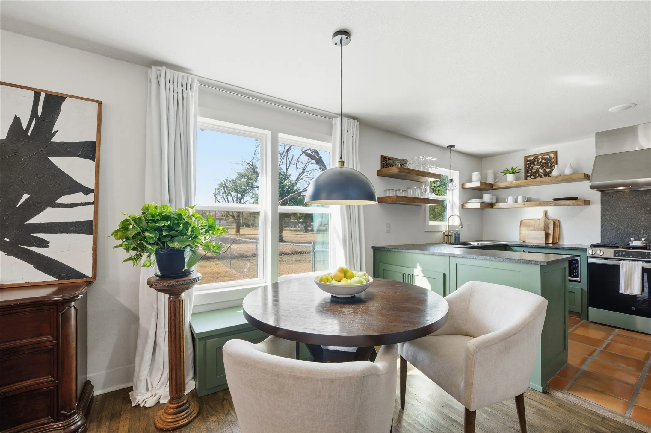 Modern kitchen featuring green cabinetry, open wood shelving, stainless steel appliances, and a tiled floor