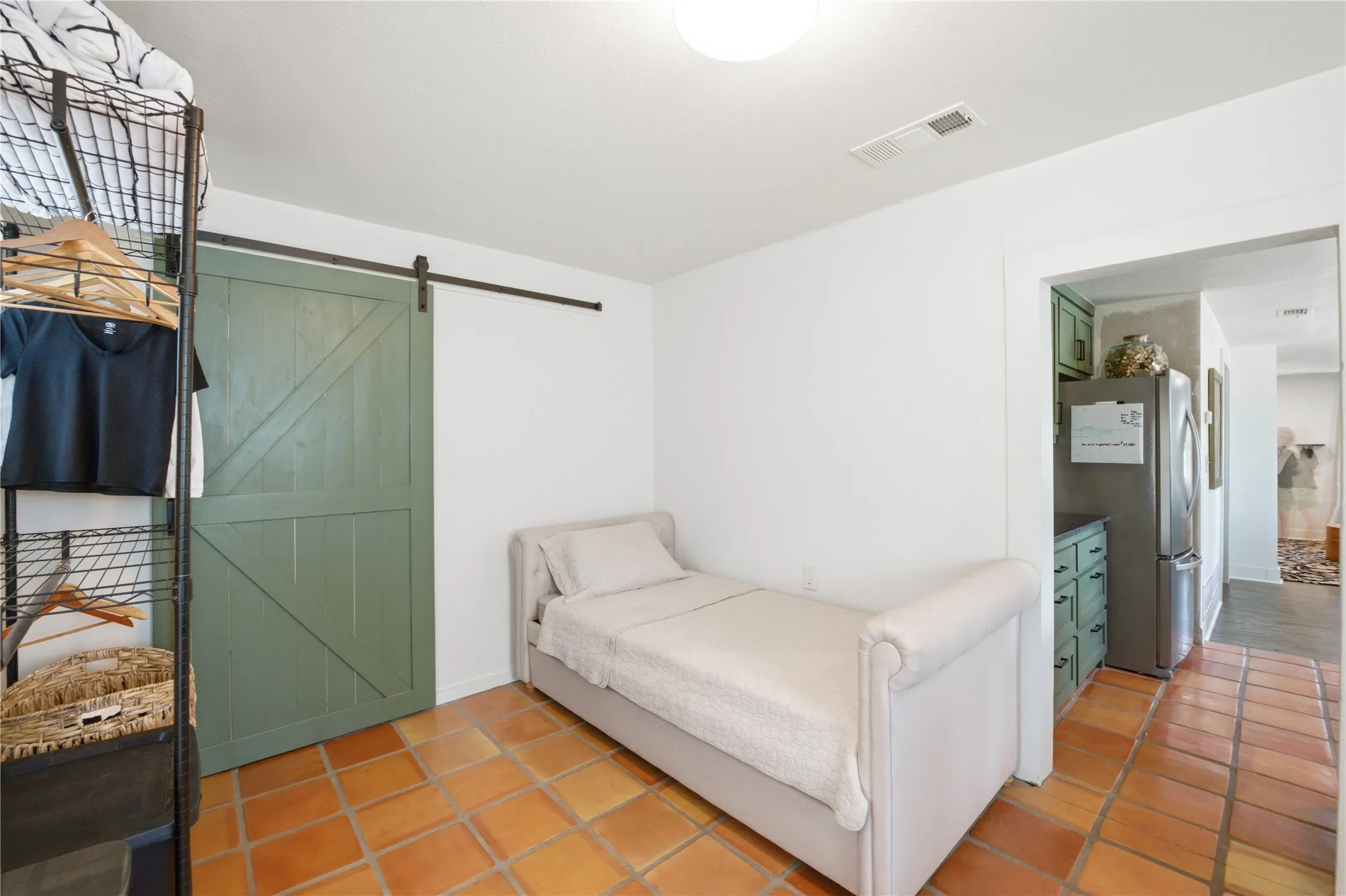 Terracotta tile flooring, white walls, and a green barn door