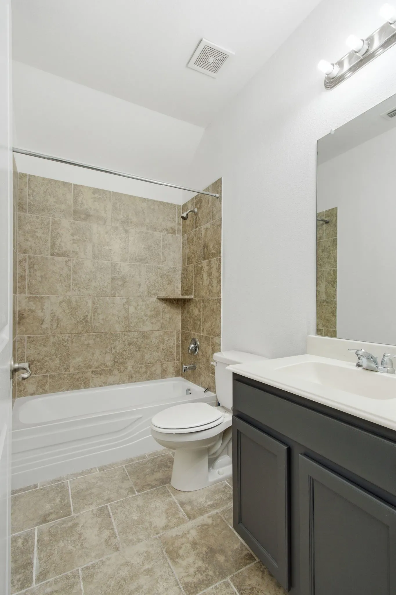 Full bathroom featuring a tub/shower combination with tile surround, tile flooring, and a vanity with a white countertop