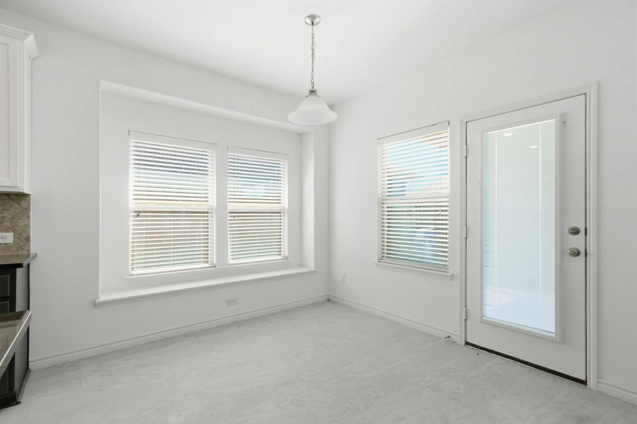 Recessed window bay with multiple windows, glass-paneled exterior door, pendant lighting, built-in cabinetry with stone-finish countertop, and wall-to-wall carpeting