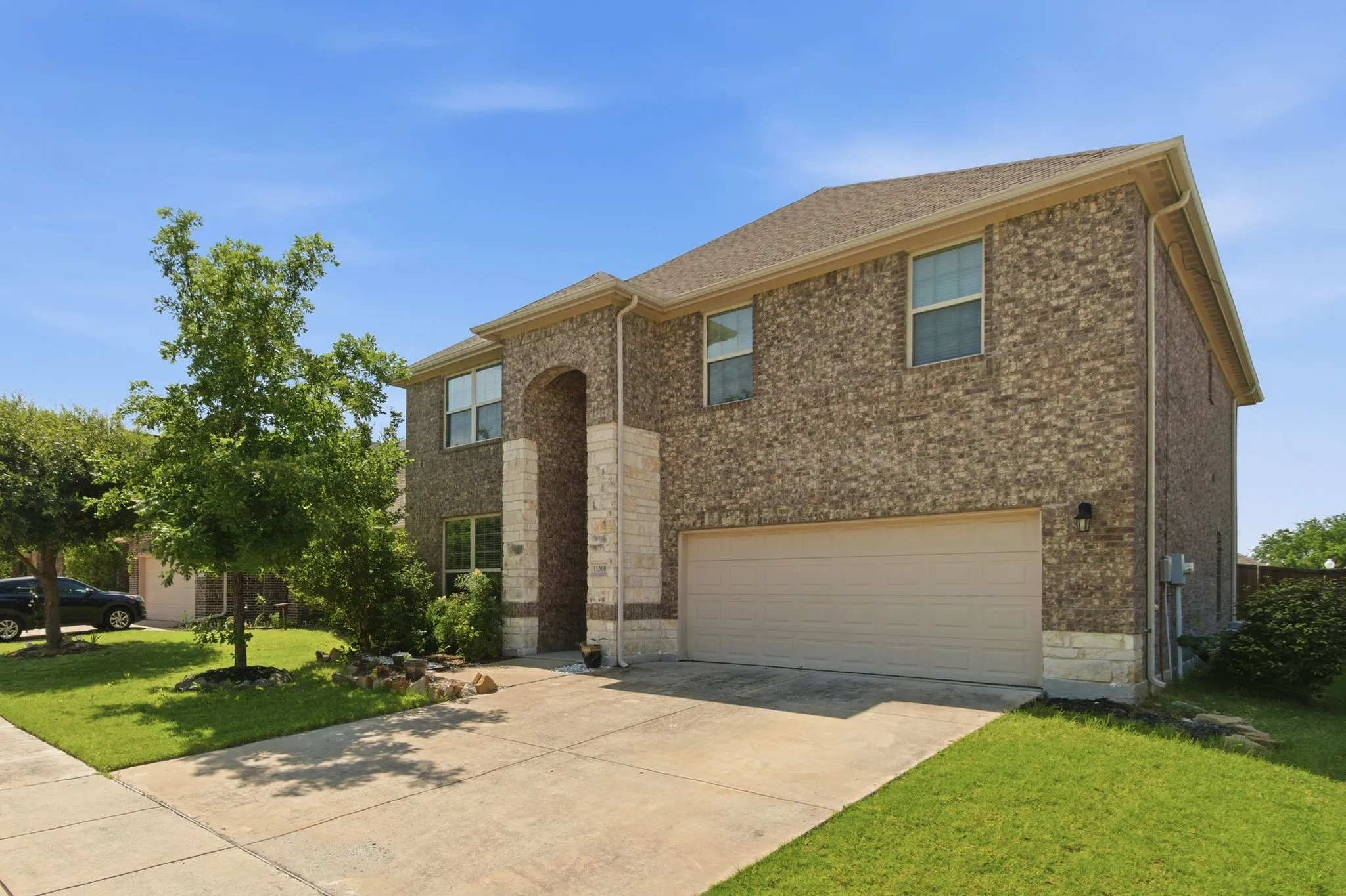 Two-story brick exterior, attached garage, concrete driveway, and a shingle roof