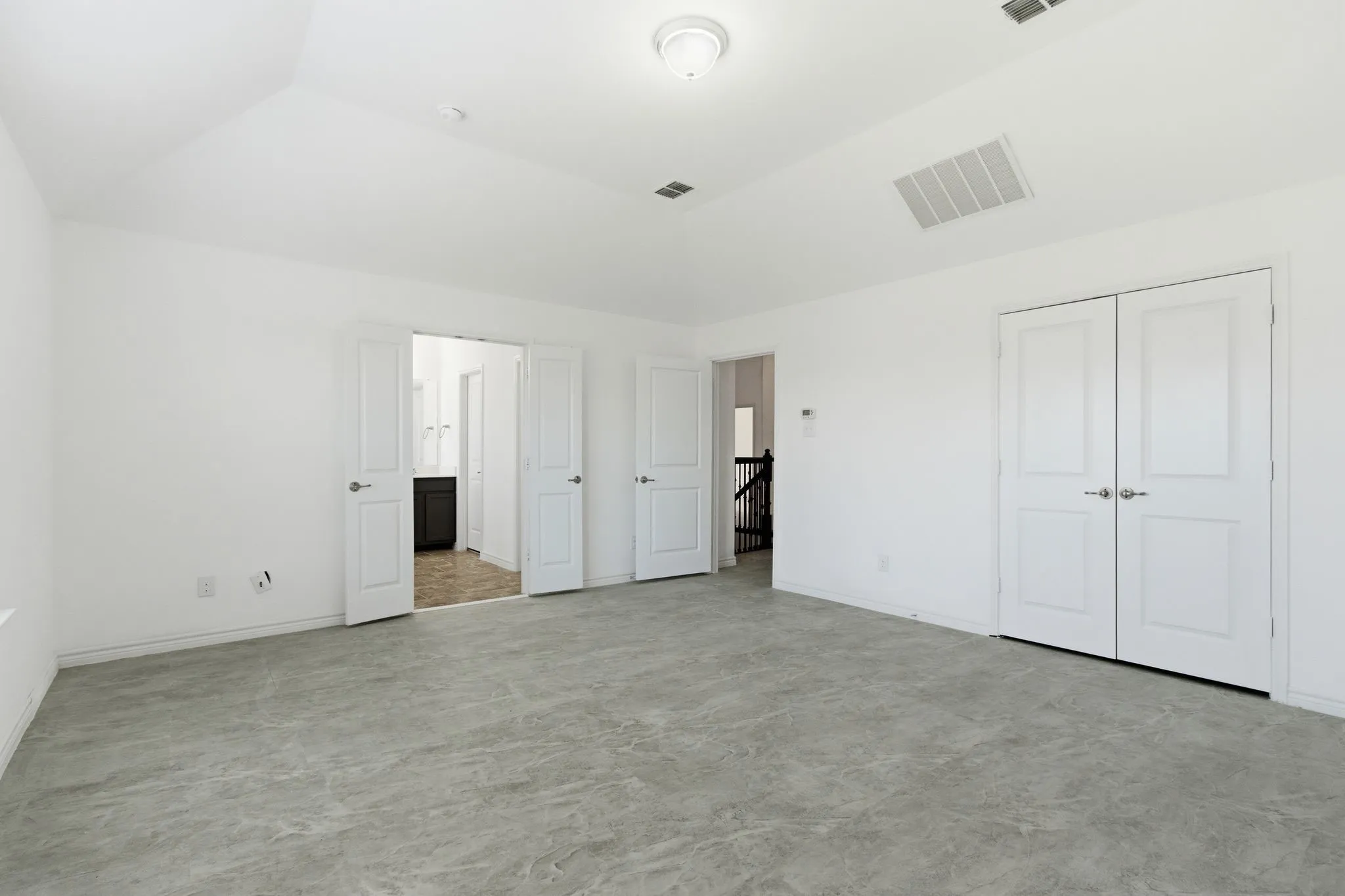 Expansive room featuring gray-toned flooring, white walls, and a tray ceiling
