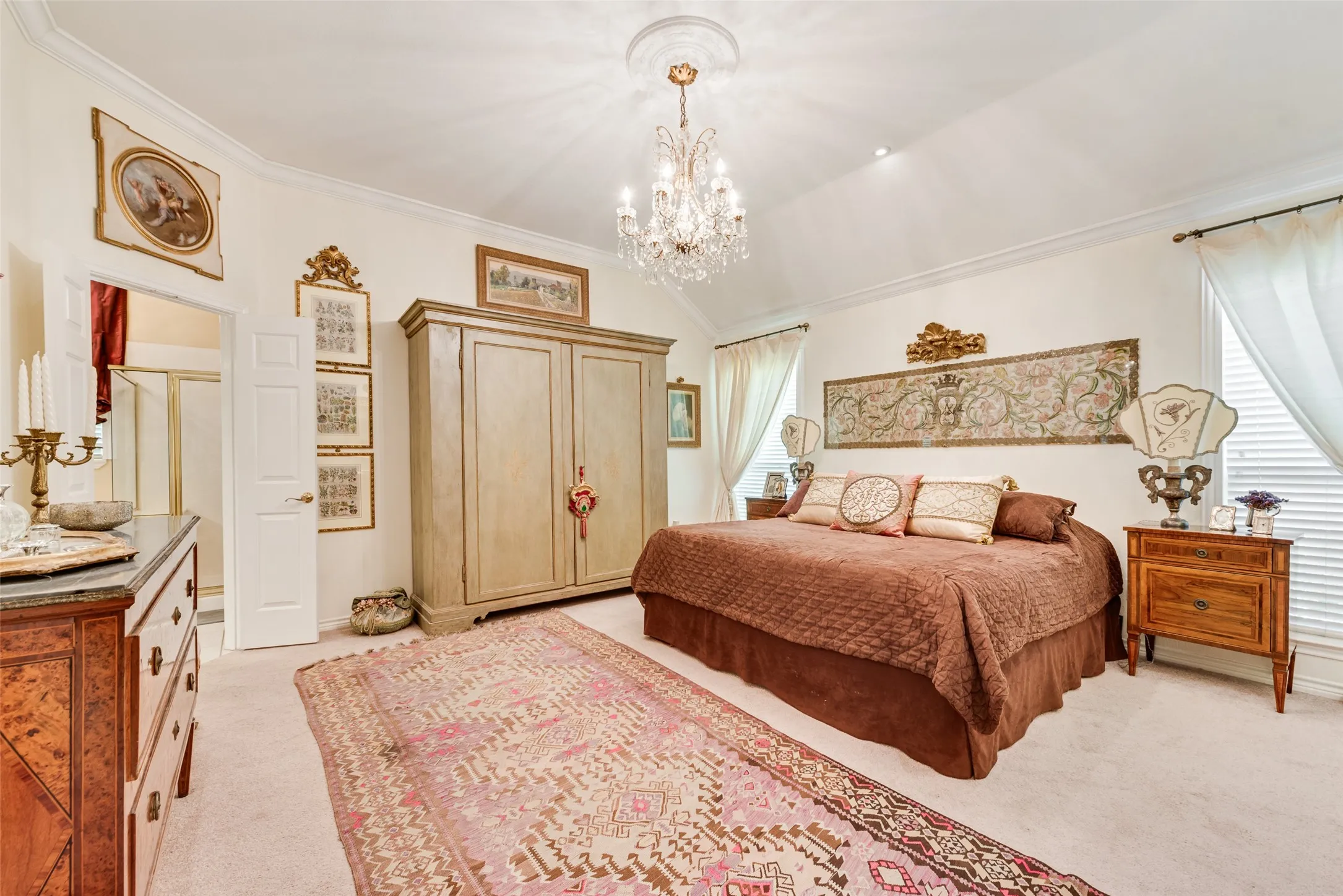 Vaulted ceiling with crown molding, crystal chandelier, and recessed lighting