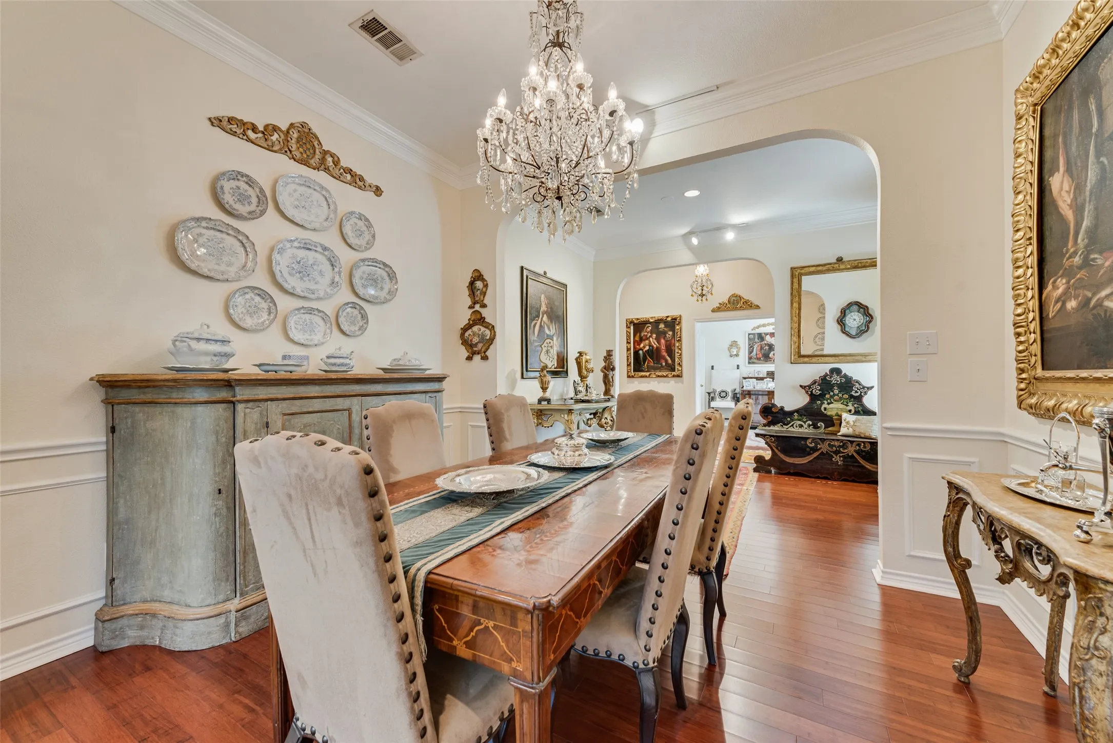 Hardwood-finish flooring, crown molding, wainscoting, and an arched doorway