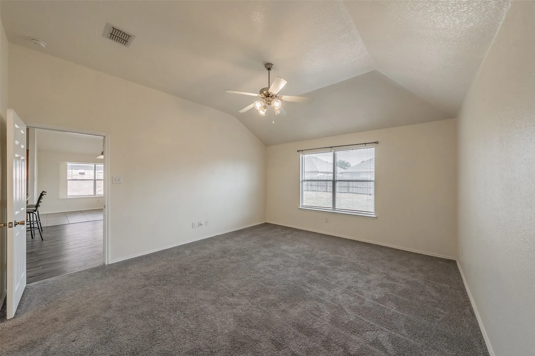 with Spacious master bedroom featuring large windows overlooking the backyard and neutral-toned carpeting.