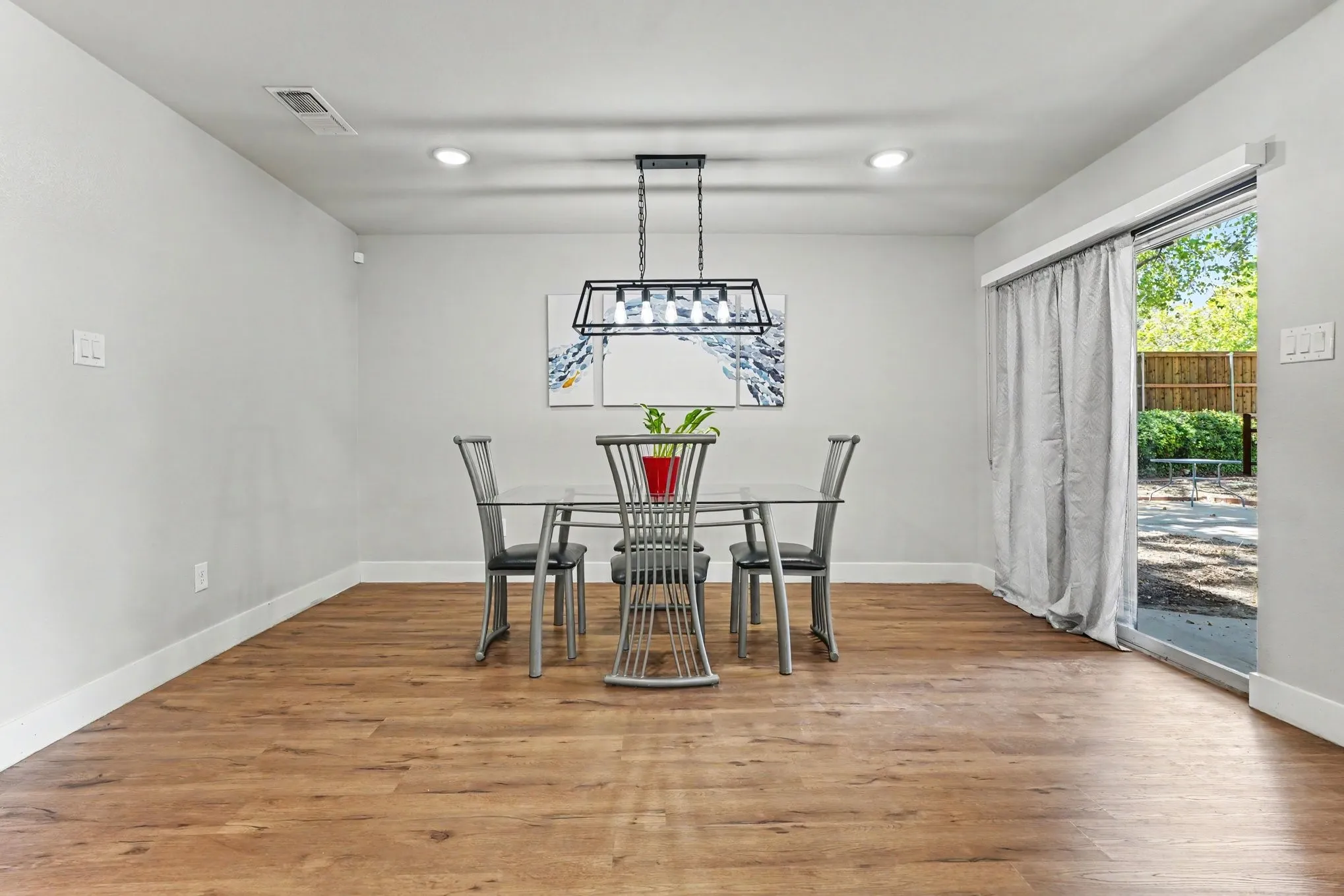 Wood-finish flooring with white baseboards, recessed lighting, and a contemporary linear chandelier