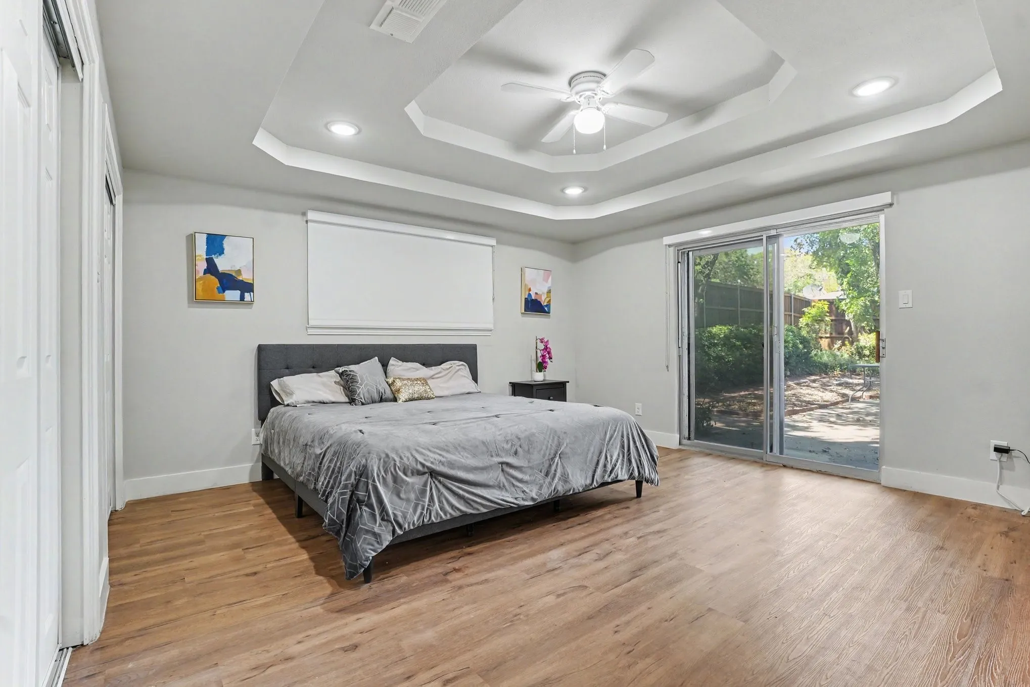 Tray ceiling with recessed lighting and ceiling fan, wood-finish flooring, and sliding glass doors