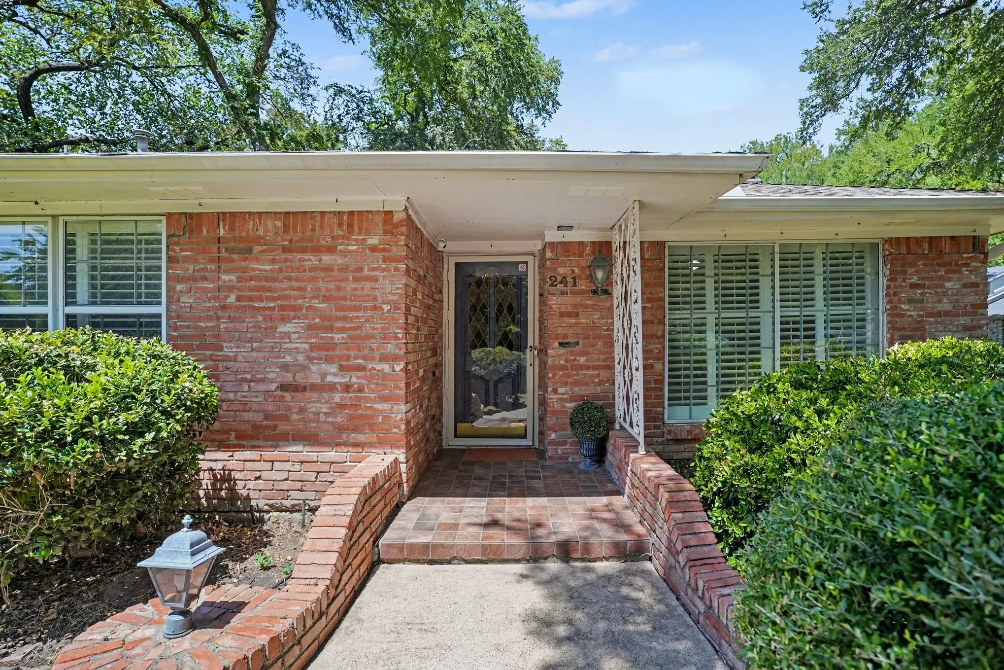 Brick exterior with covered entry, decorative security door, and plantation shutters