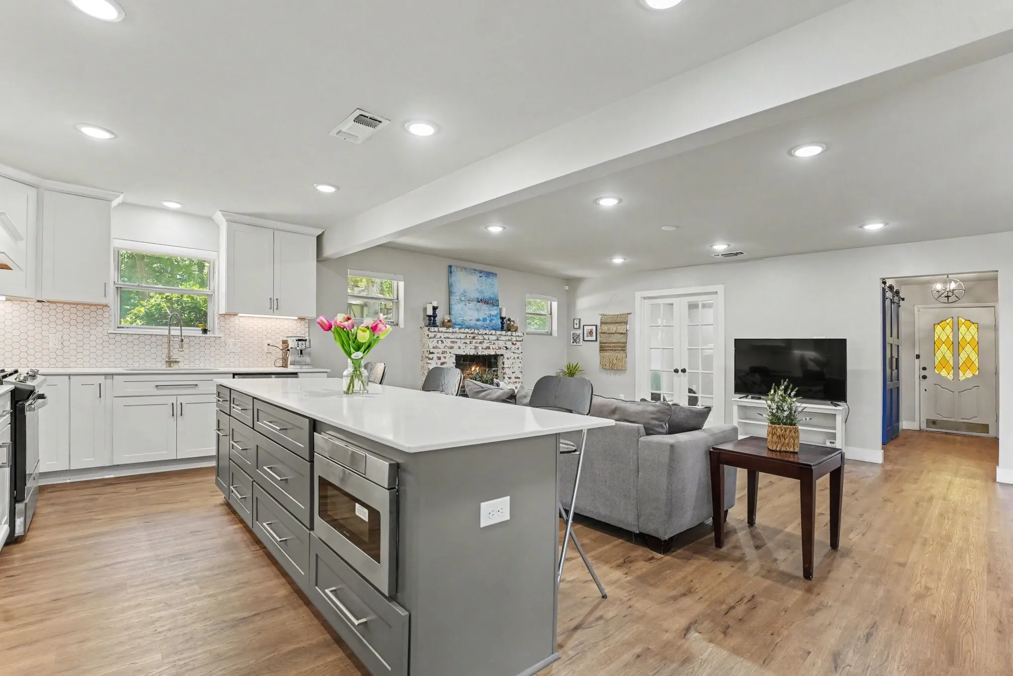 Kitchen island with integrated microwave, white shaker cabinetry, hexagonal tile backsplash, wood-finish flooring, and recessed lighting
