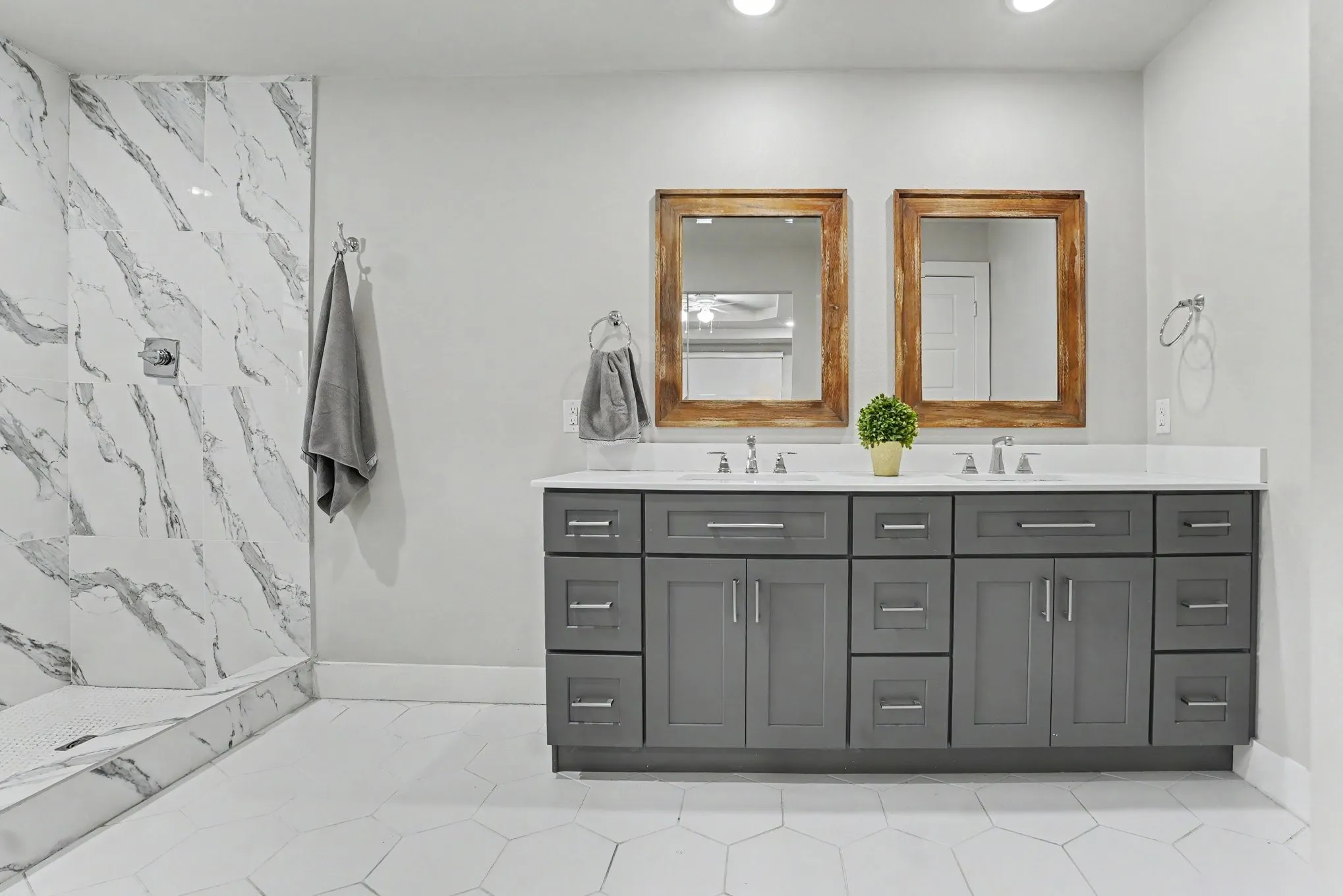 Dual vanity with a white countertop and gray cabinetry, complemented by two framed mirrors