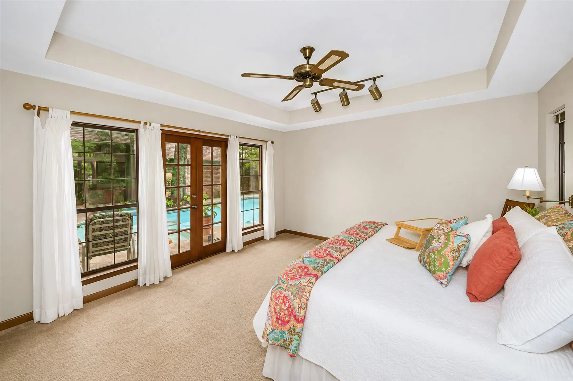 Light and bright primary bedroom features an ensuite bath and overlooks the sparkling pool.