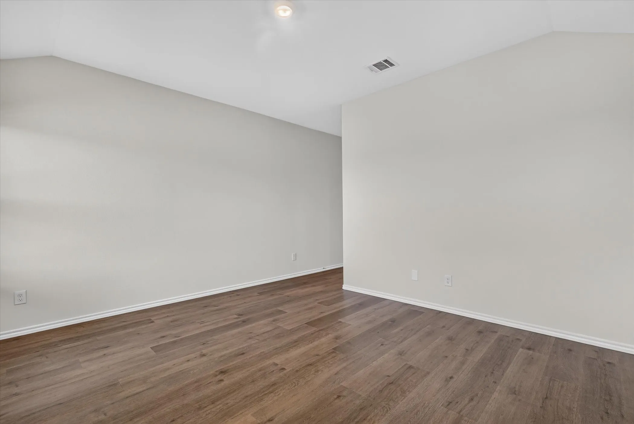 Vaulted ceiling with recessed lighting, light neutral wall paint, wood-finish flooring, and white trim
