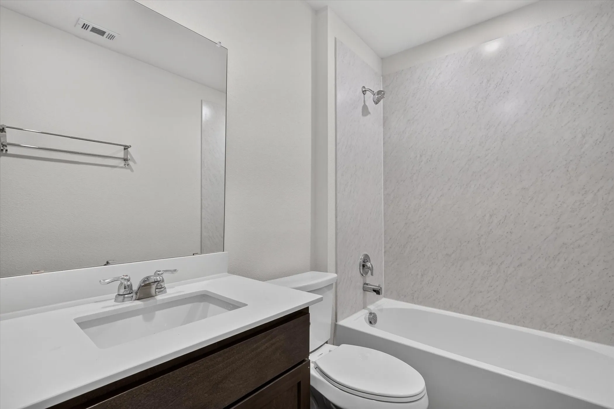Integrated vanity with a rectangular sink, polished chrome faucet, and dark wood-finish cabinetry
