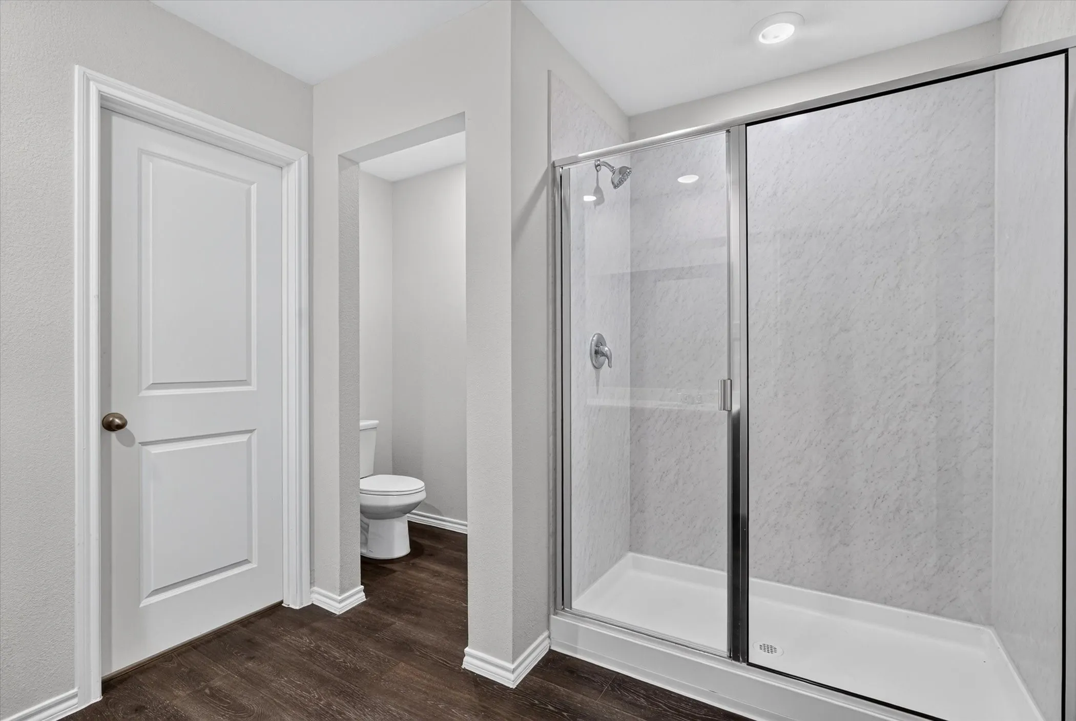 Walk-in shower with clear glass enclosure, white shower base, and textured wall surround