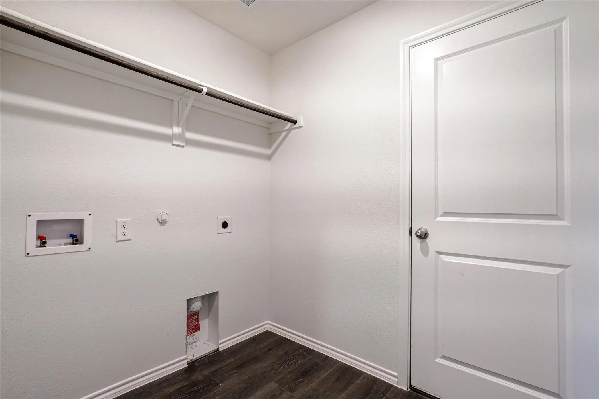 Utility connections, wood-finish flooring, white walls, built-in shelving, panel door