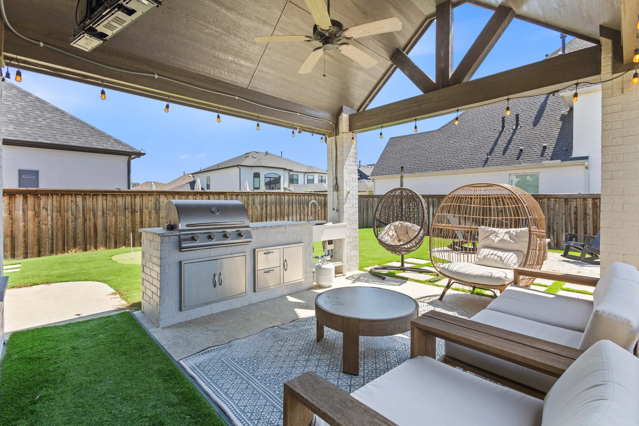 Covered patio featuring an outdoor kitchen with stainless steel appliances, exposed beam vaulted ceiling, and string lighting