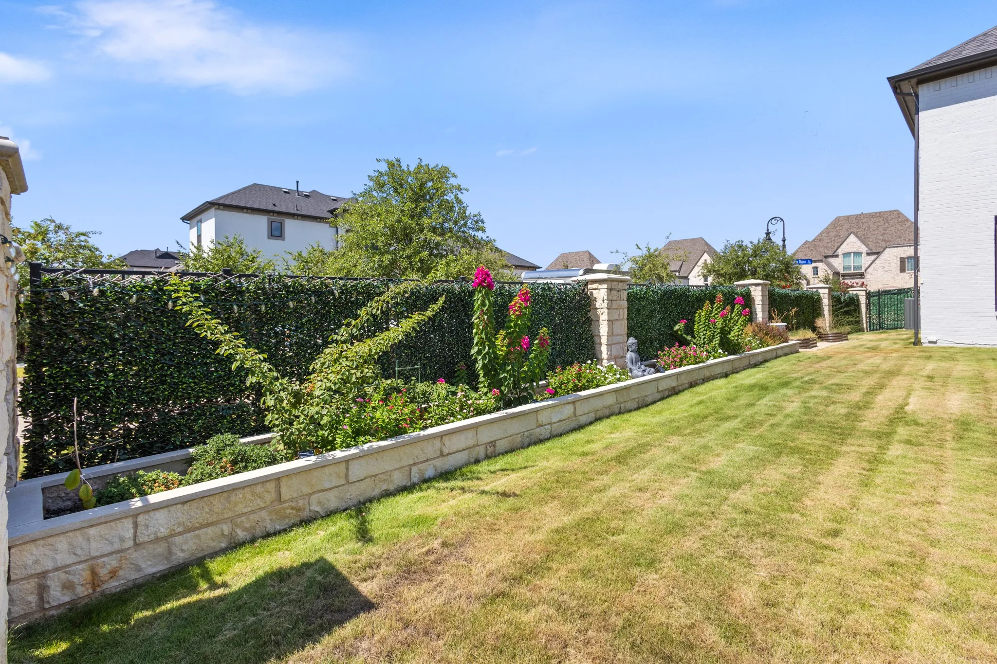 Expansive grassy yard with a stone-faced retaining wall and integrated garden beds
