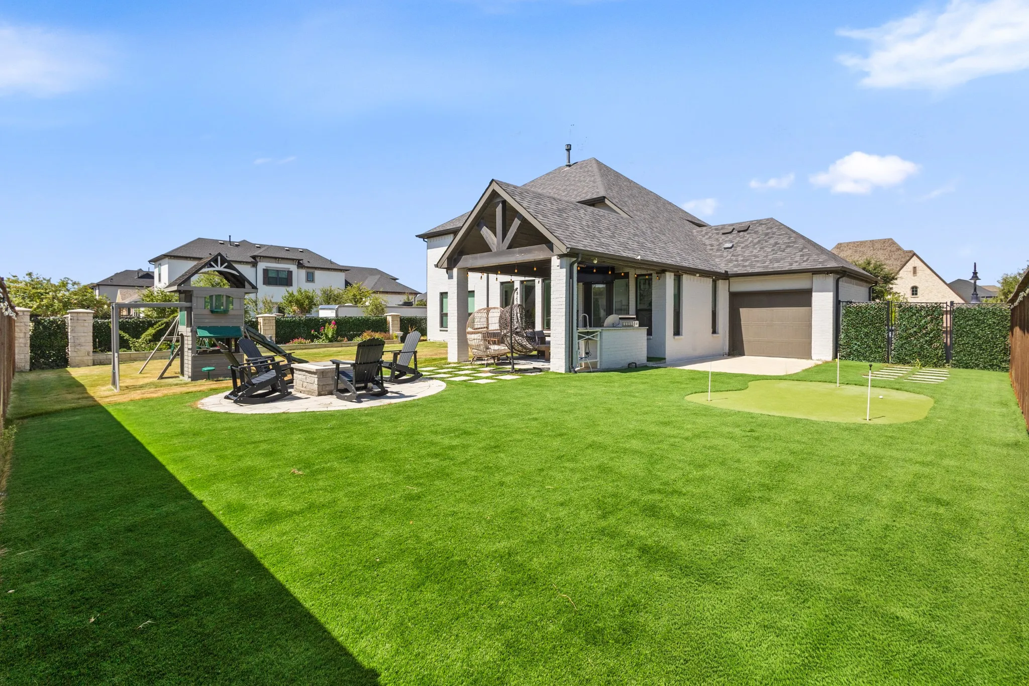 Expansive backyard with a putting green, paved patio, and a dedicated fire pit area