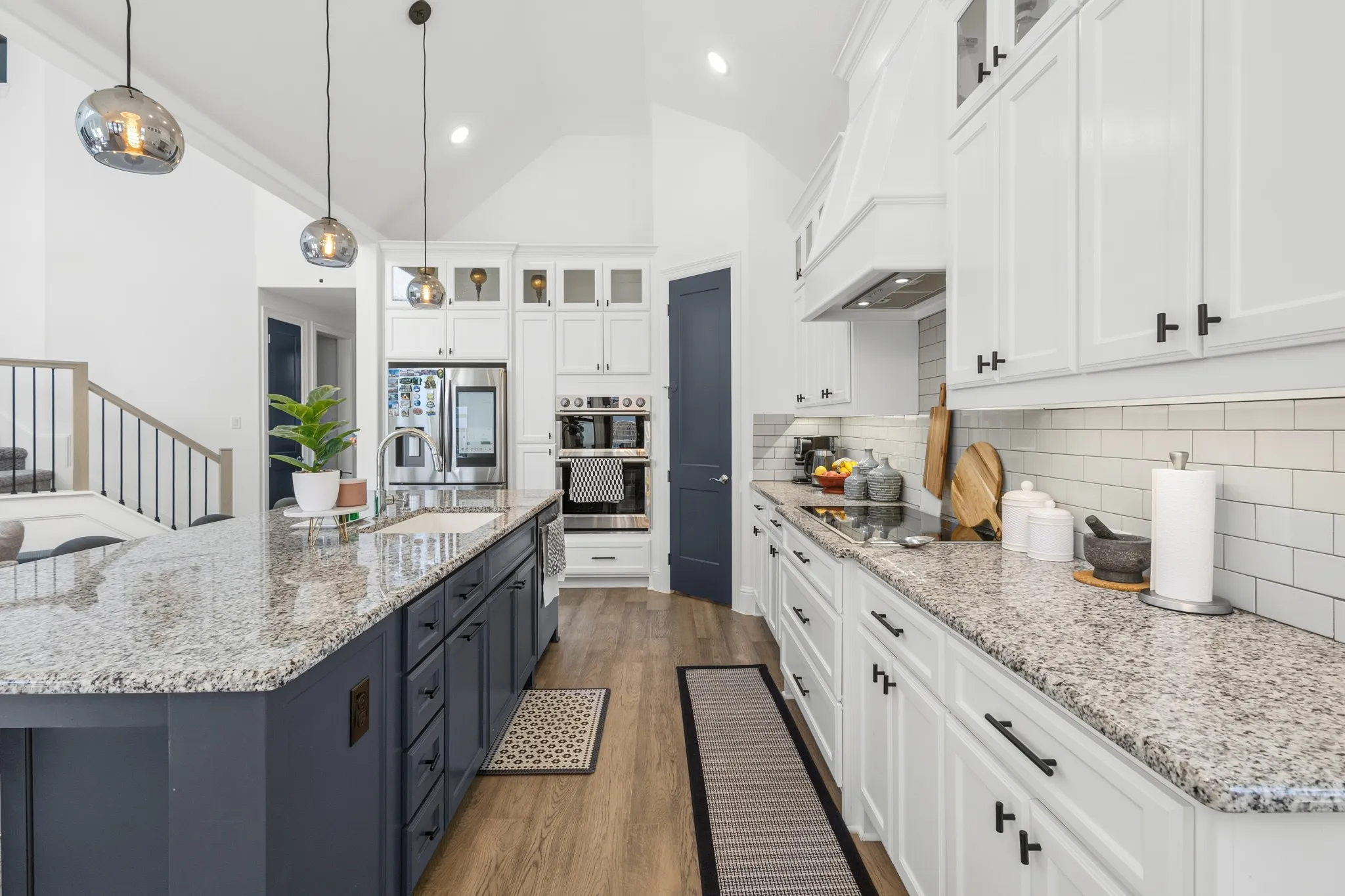 Expansive kitchen island with a built-in sink, stone countertop, and pendant lighting