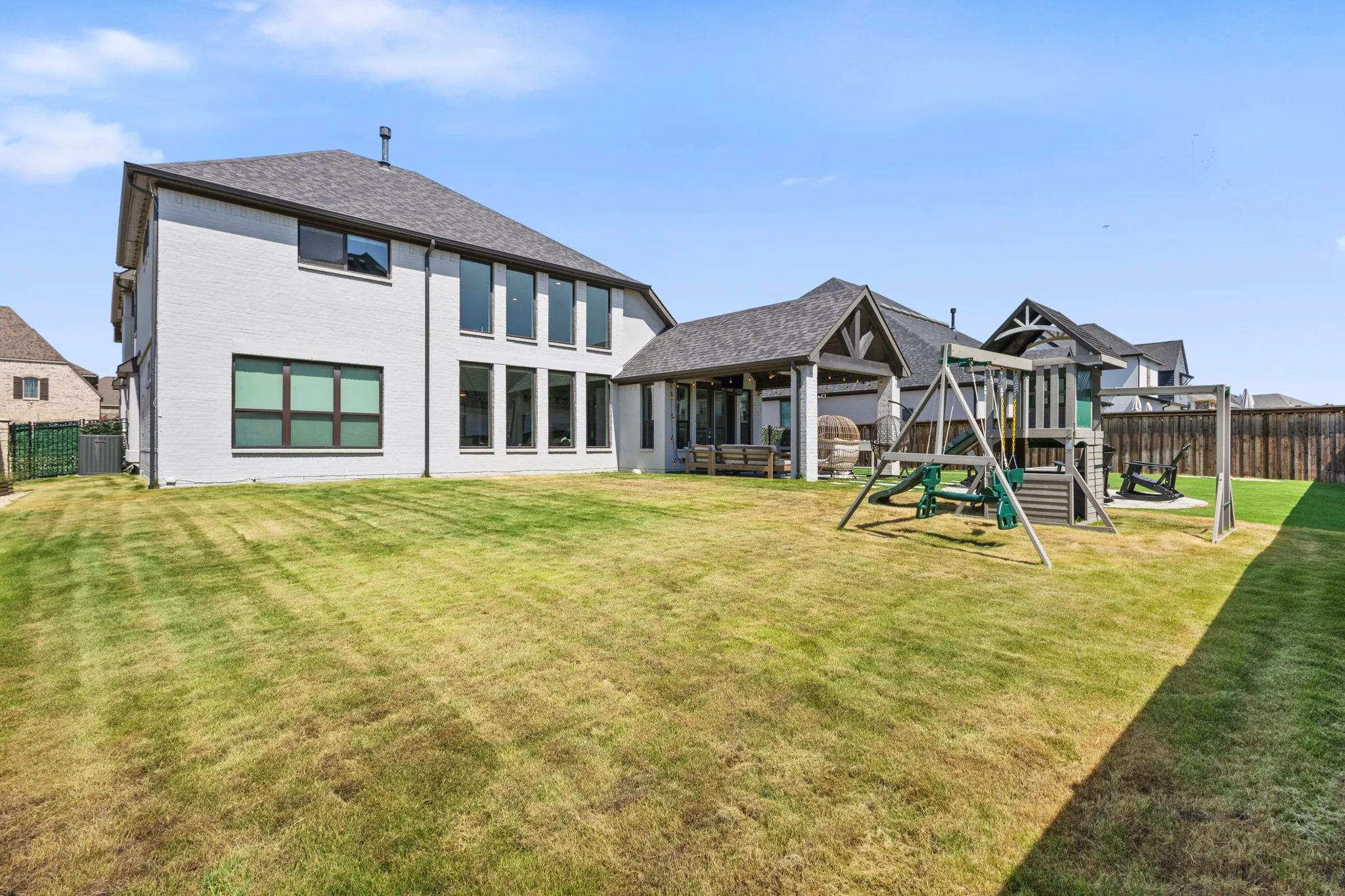 Expansive backyard featuring a manicured lawn, a covered outdoor living area, and a privacy fence