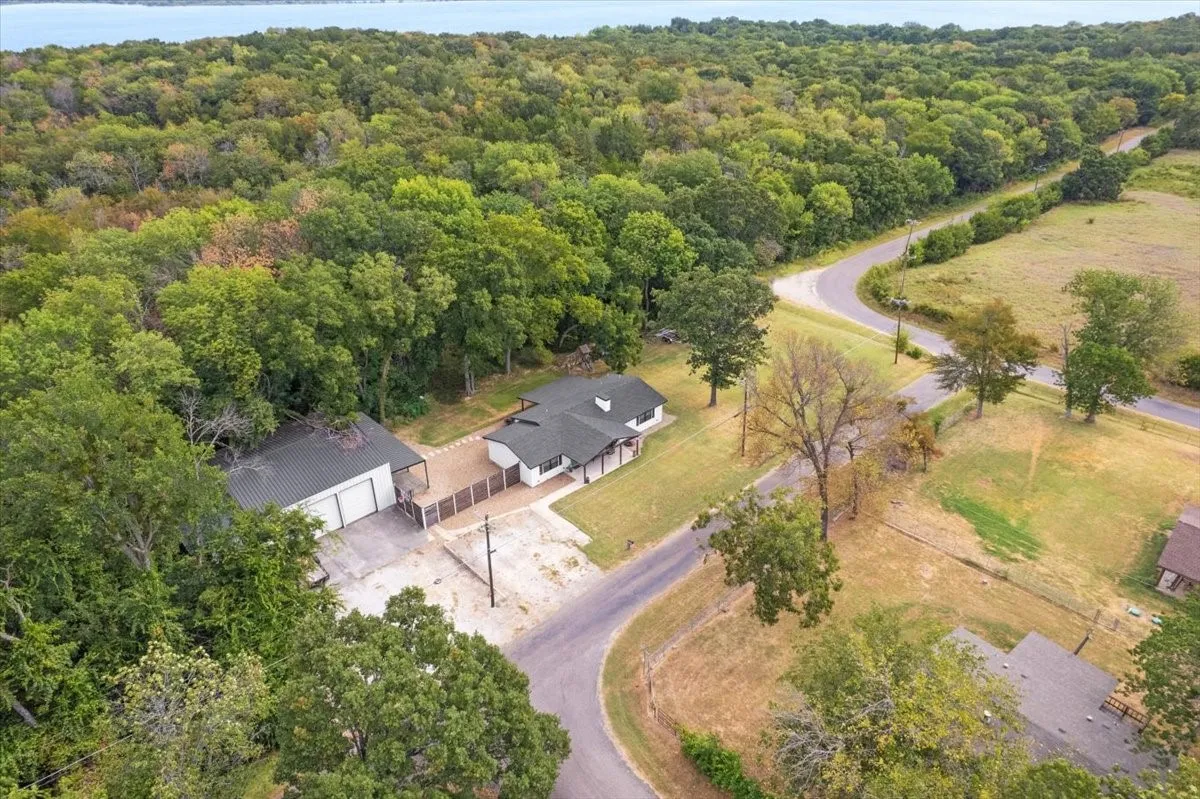 Expansive wooded surroundings with a curving road, a 40x40 shop, and a single-story residence