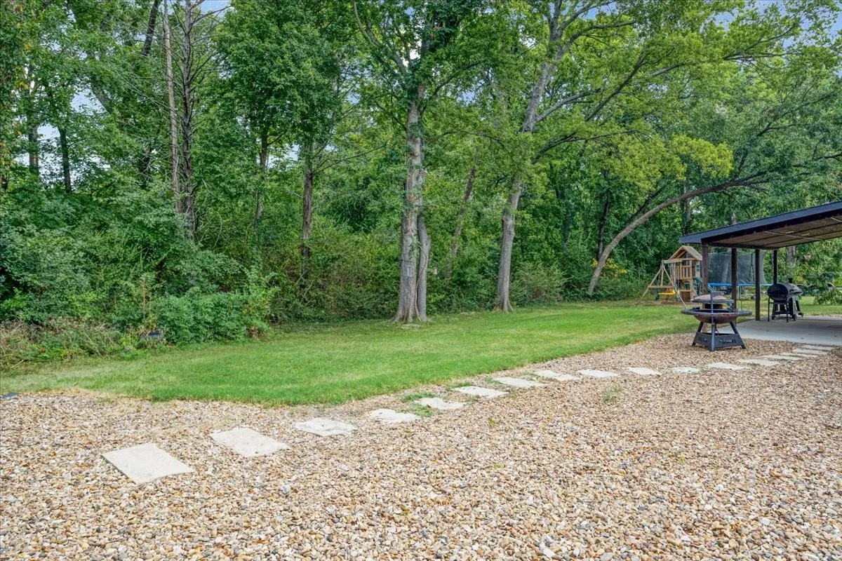 Expansive backyard featuring a gravel patio, stepping stones, and a covered outdoor area