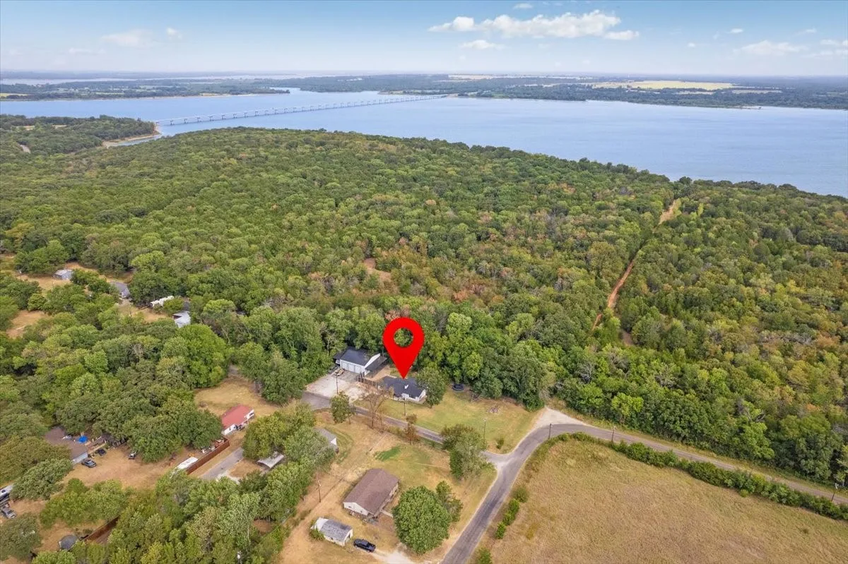 Aerial perspective showcasing a property surrounded by expansive tree coverage with a large body of water in the background