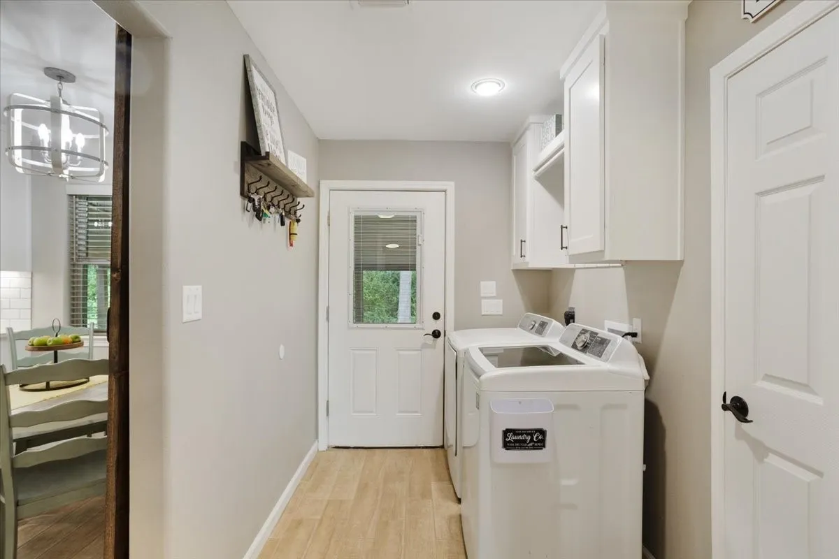 Laundry area with wood-finish flooring, white cabinetry, recessed lighting, and a door with an integrated window