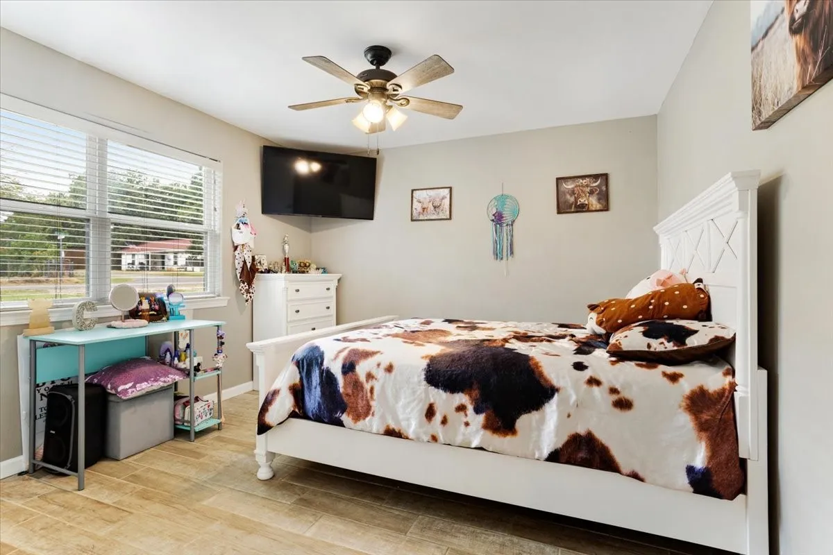 Wood-finish flooring, neutral wall tones, and a ceiling fan with integrated lighting