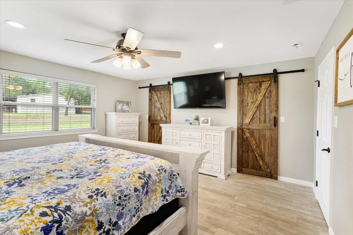 Recessed lighting, ceiling fan, wood-finish flooring, white trim, and a rustic wood barn door
