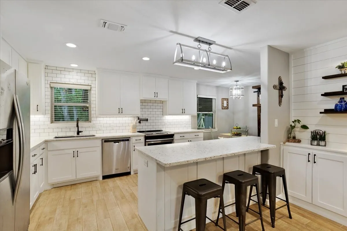 Kitchen featuring white cabinetry, subway tile backsplash, recessed lighting, wood-finish flooring, and a center island with countertop seating