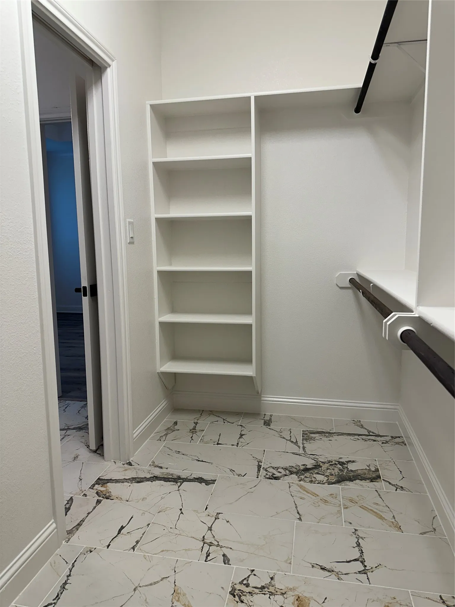White built-in shelving, integrated hanging rods, and patterned tile flooring