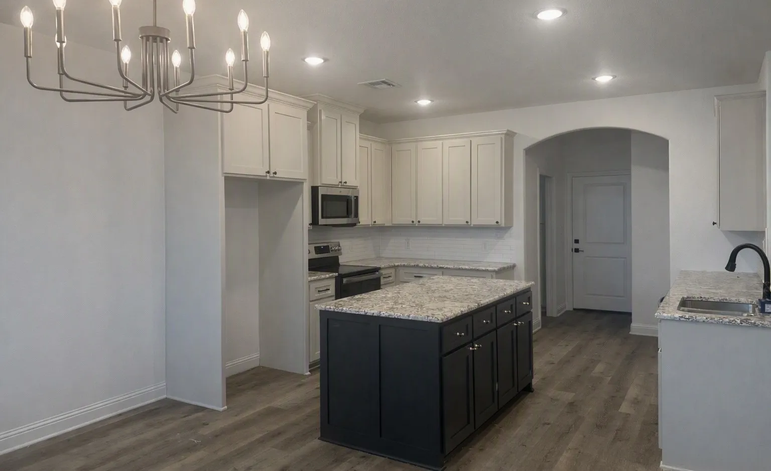 Kitchen featuring a central island with countertop, wood-finish flooring, white cabinetry, integrated stainless steel appliances, and recessed lighting