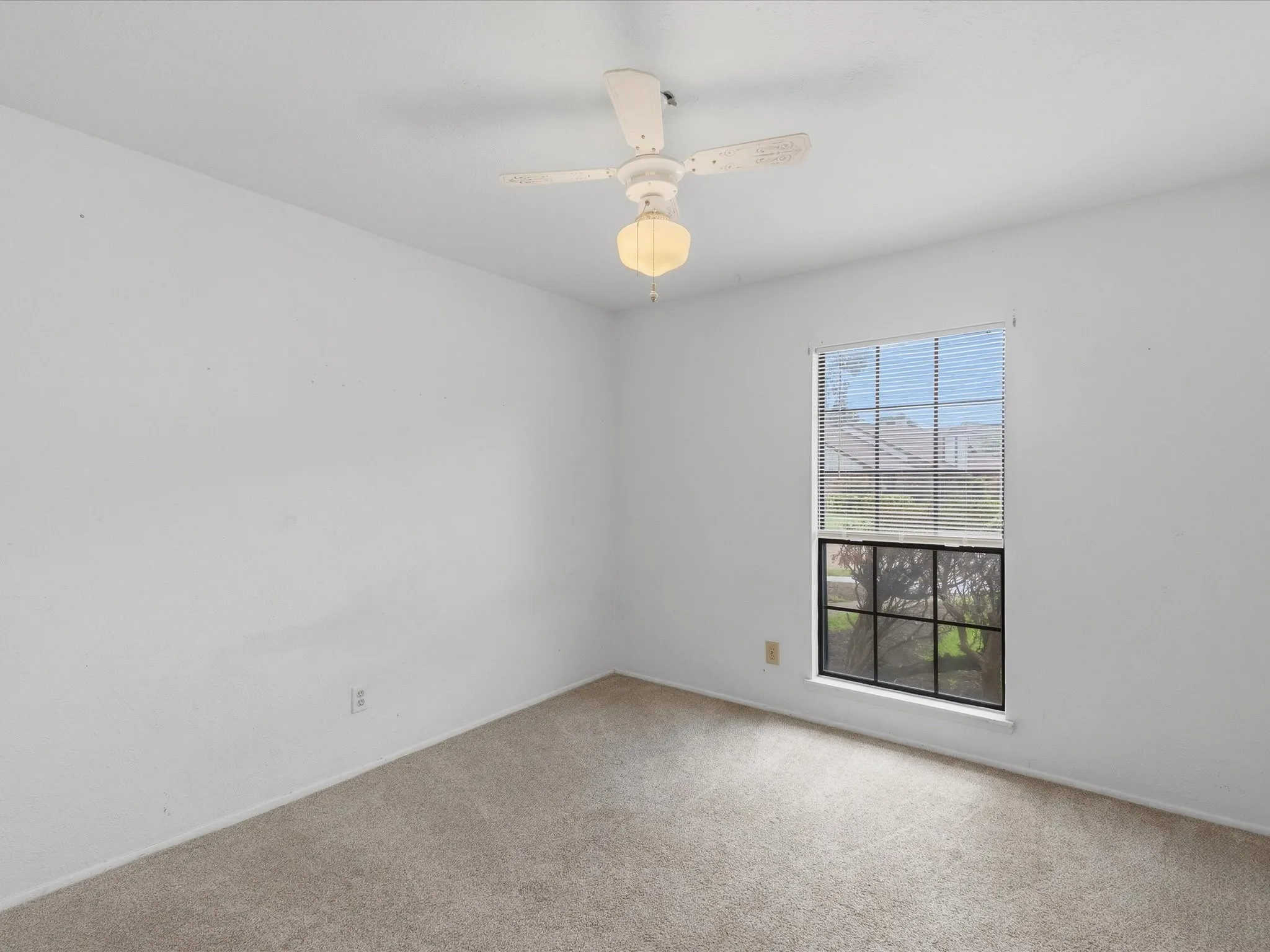 Neutral carpet flooring, white walls, and a ceiling fan with integrated lighting