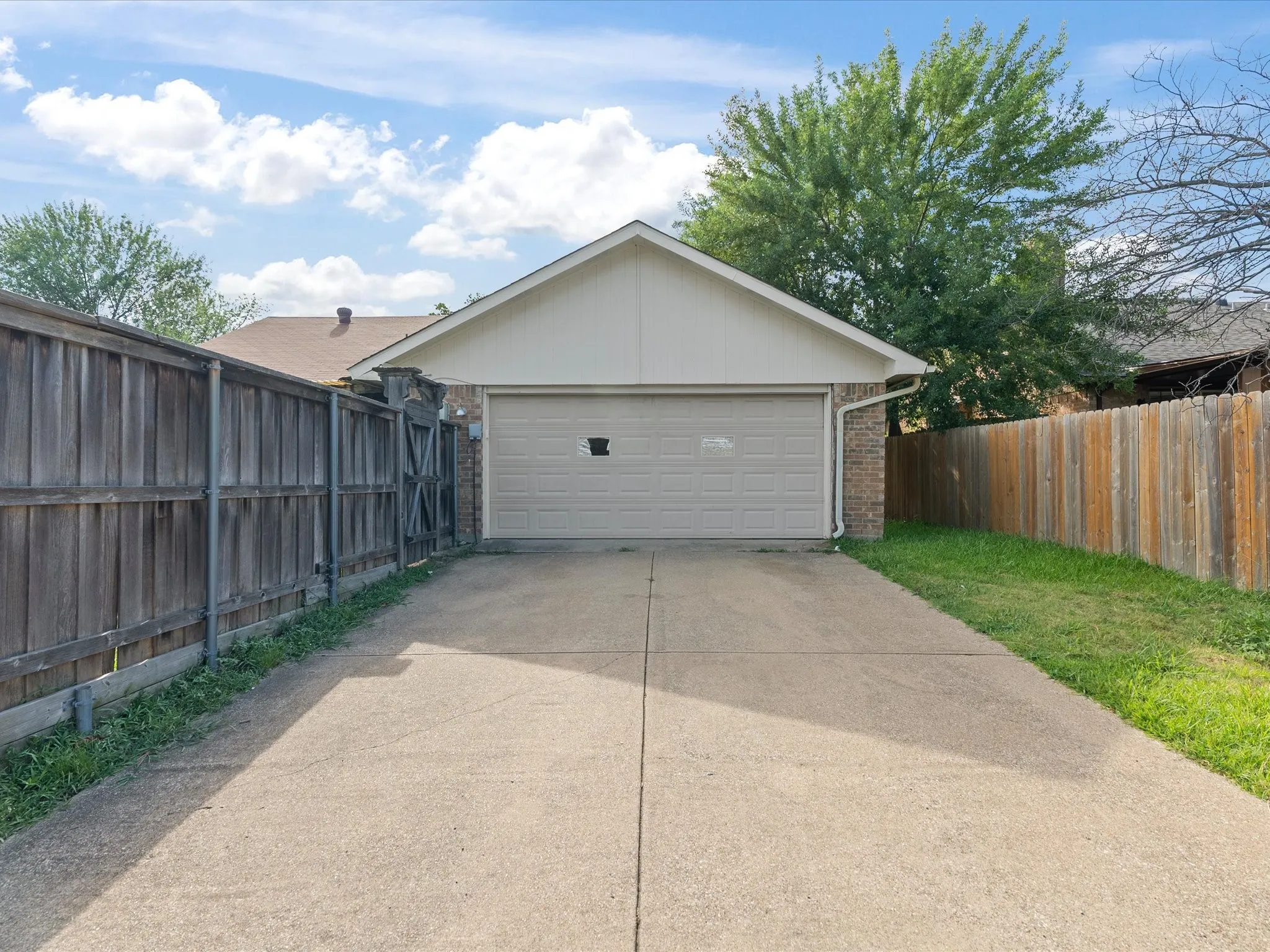 Attached garage with brick facade and light-toned siding